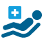 Icono azul de paciente encamillado y recostado con un cuadrado azul más claro por encima de sus piernas con una cruz blanca